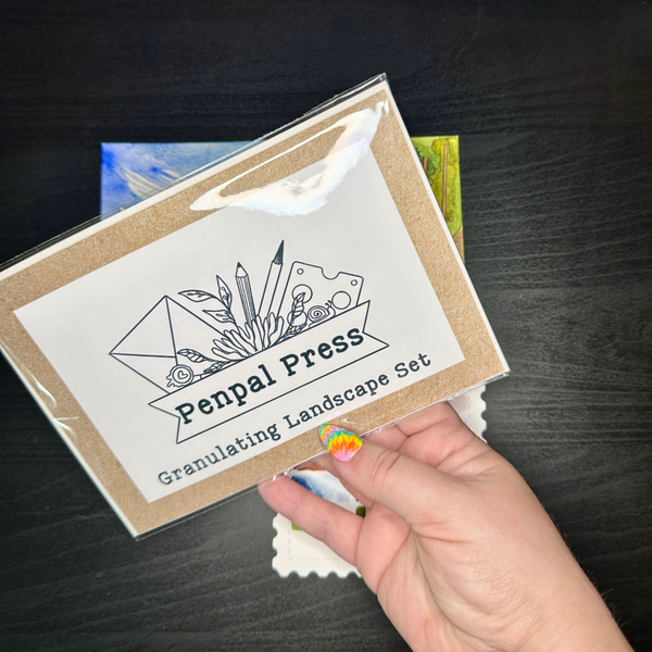 Penpal Press granulating landscape set packaging held by a hand on a dark surface