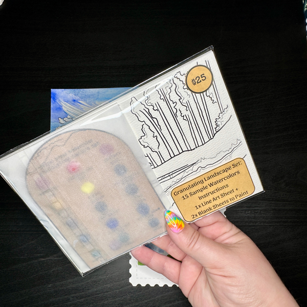 Hand holding a paint palette and watercolor set packaging on a dark surface