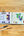 Open art supply set with watercolor paints and a drawing of blueberries and strawberry on a wooden surface.
