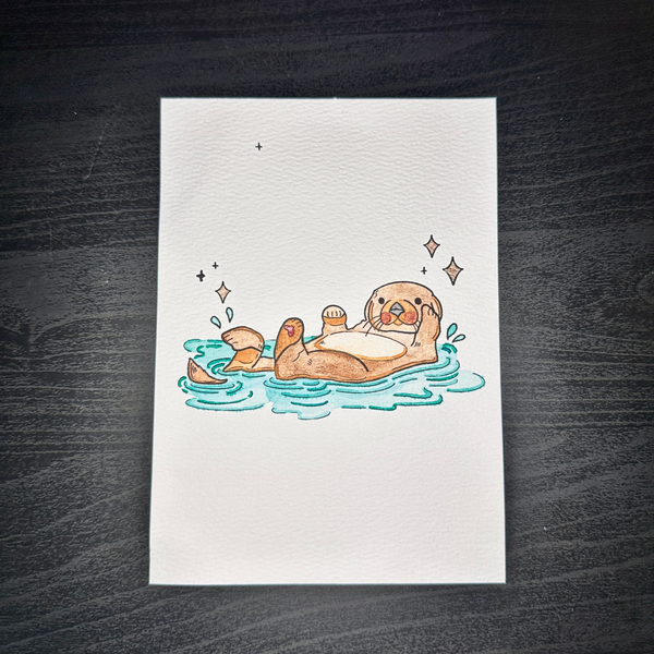 Watercolor painting of a sea otter floating in water with iridescent stars.