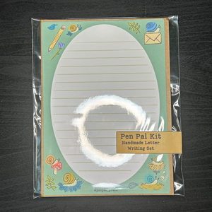 Pen Pal Kit with lined paper and stationery items on a dark surface
