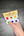 Hand holding a paint set with color samples against a dark wooden surface