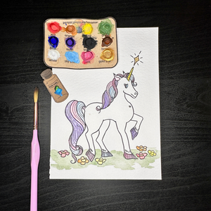 Watercolor page with a unicorn, paint palette, paintbrush, and paint samples.