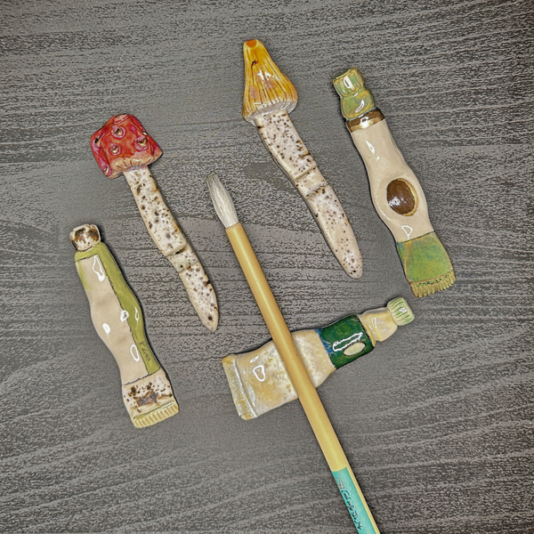 Set of ceramic art pieces resembling mushrooms and bottles on a textured surface