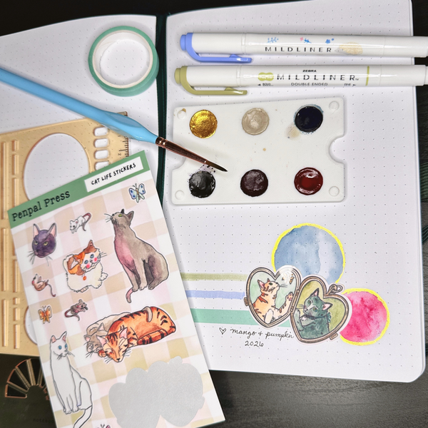 Sticker sheet with cat illustrations, paint palette, and markers on a dark surface