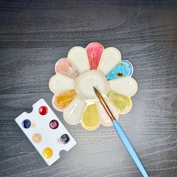 Colorful paint palette with a brush on a gray surface