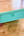 Green box with 'Penpal Press Watercolor' text held by a hand on a wooden surface