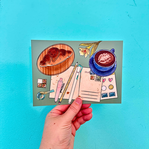 Illustrated postcard with a cup of coffee, croissants, and stationery items held against a blue background.