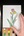 Hand holding a drawing of tulips with a paintbrush and color swatches on a dark surface