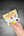Hand holding a paint set with yellows, orange, violet, and more.