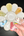 Hand holding a flower-shaped color palette with various colors on a dark background