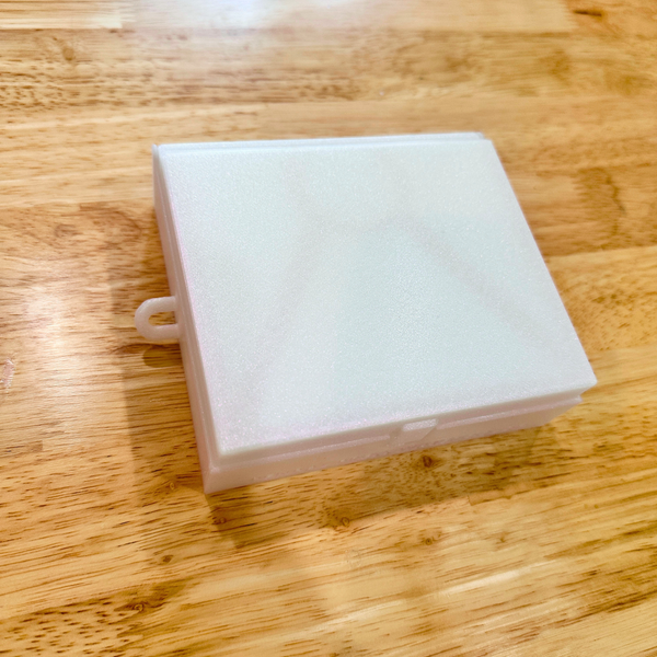 White iridescent paint box on wooden surface.