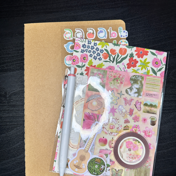 Notebook with stickers and a pen on a dark surface