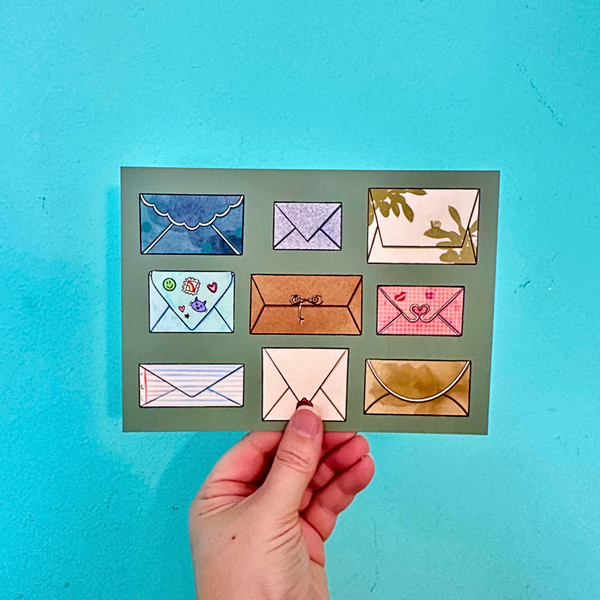 Hand holding a card with colorful envelope designs against a blue background