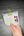 Packaged stationery items including colorful watercolor paint and a clip held by a hand on a dark surface.
