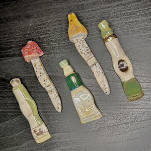 Set of five ceramic or stone tools with different designs on a textured surface