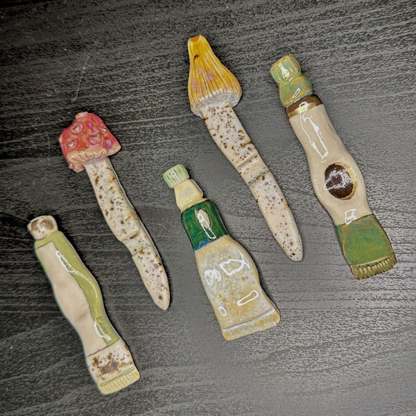 Set of five ceramic or stone tools with different designs on a textured surface