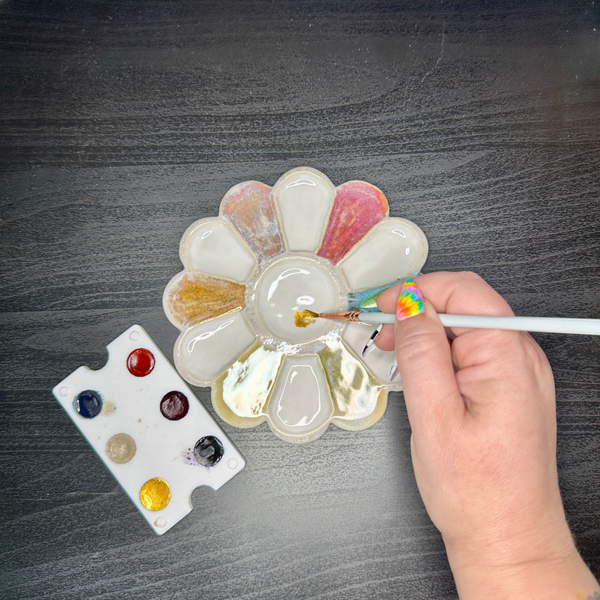Hand painting on a ceramic flower with a brush on a gray surface