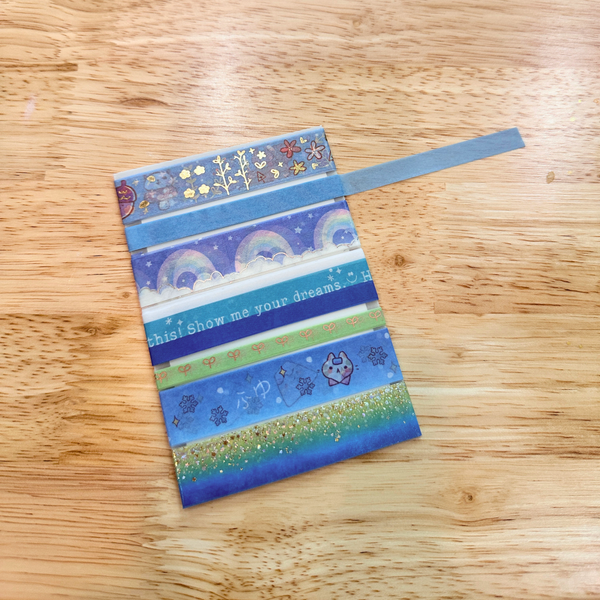 Colorful washi tape strips with patterns and text on a wooden surface.